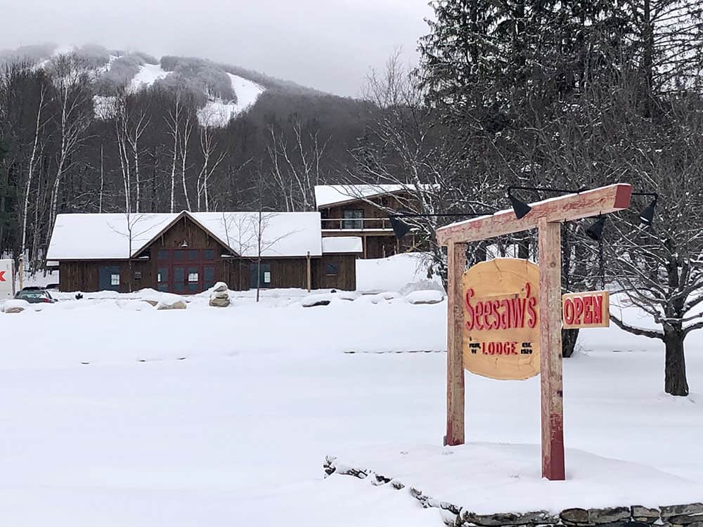Seesaws Lodge - Winter Exterior with Sign and Mountain